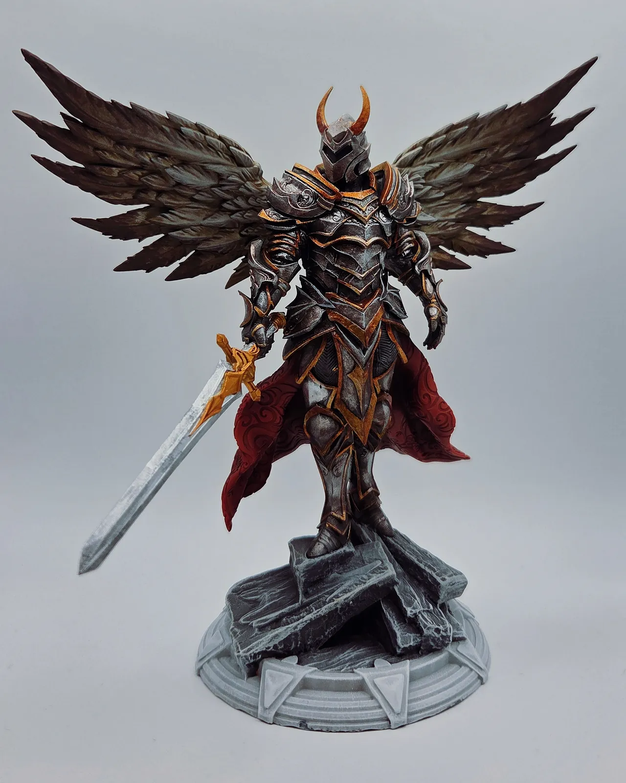 L’Archange Guerrier Paladin : un guerrier ailé en armure sombre et cape rouge, une épée à la main.