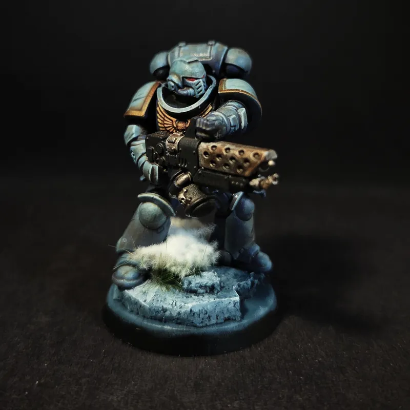 Un guerrier en armure bleue massive, une grosse arme à la main, sur un socle enneigé.