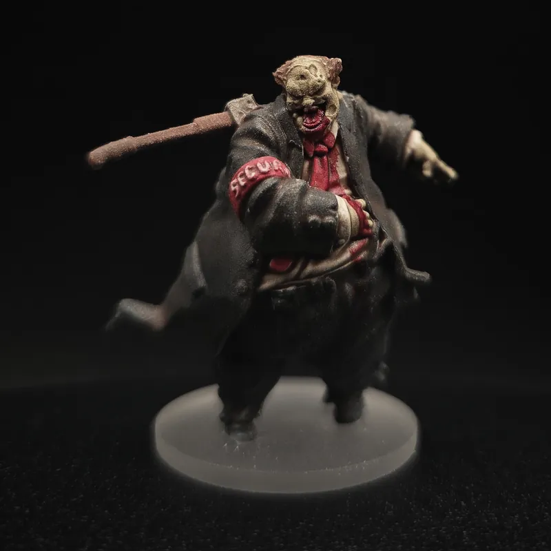 Un gros zombie en costume sombre et cravate rouge, un brassard rouge au bras et un bâton sur l’épaule.